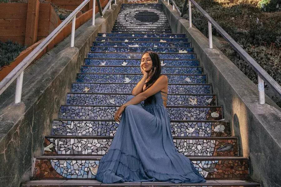 一名妇女坐在贝博体彩app日落社区第16大道的瓷砖楼梯上摆姿势.