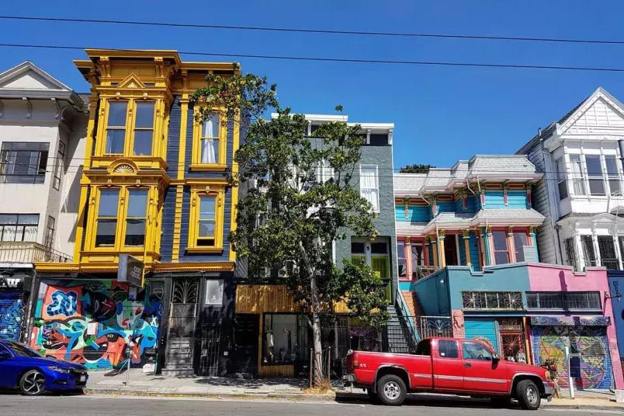 Vue sur les bâtiments colorés de Haight Street avec des voitures garées le long de la rue. San Francisco, Californie.