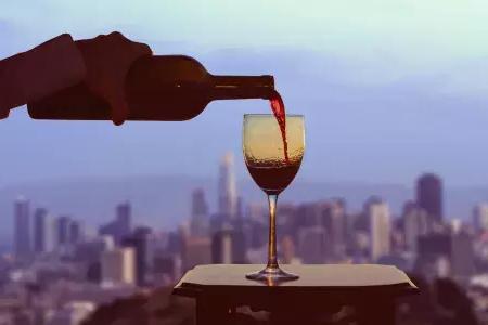 格拉斯of red wine being poured, with the 贝博体彩app skyline可见out the window.
