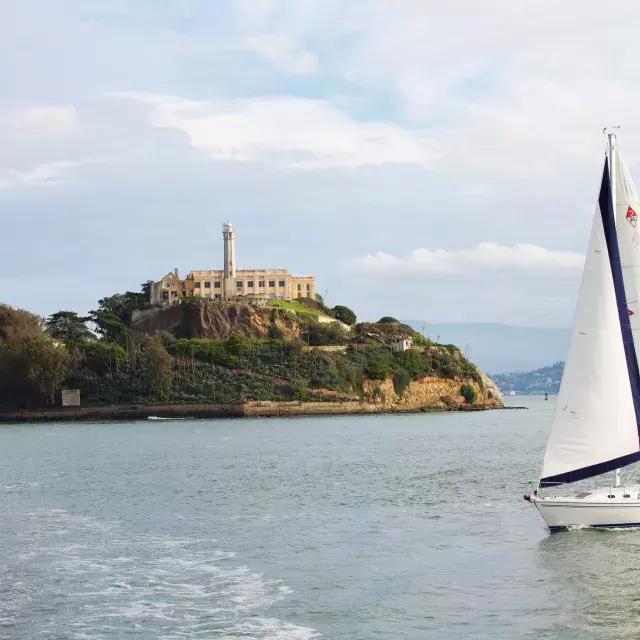 A sailboat passes in front of Alcatraz Island in San Francisco.